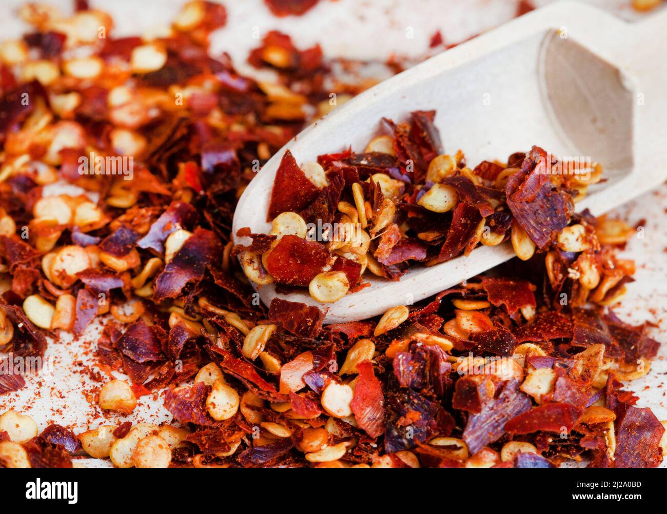 Dried red chili flakes on raw wooden surface Stock Photo