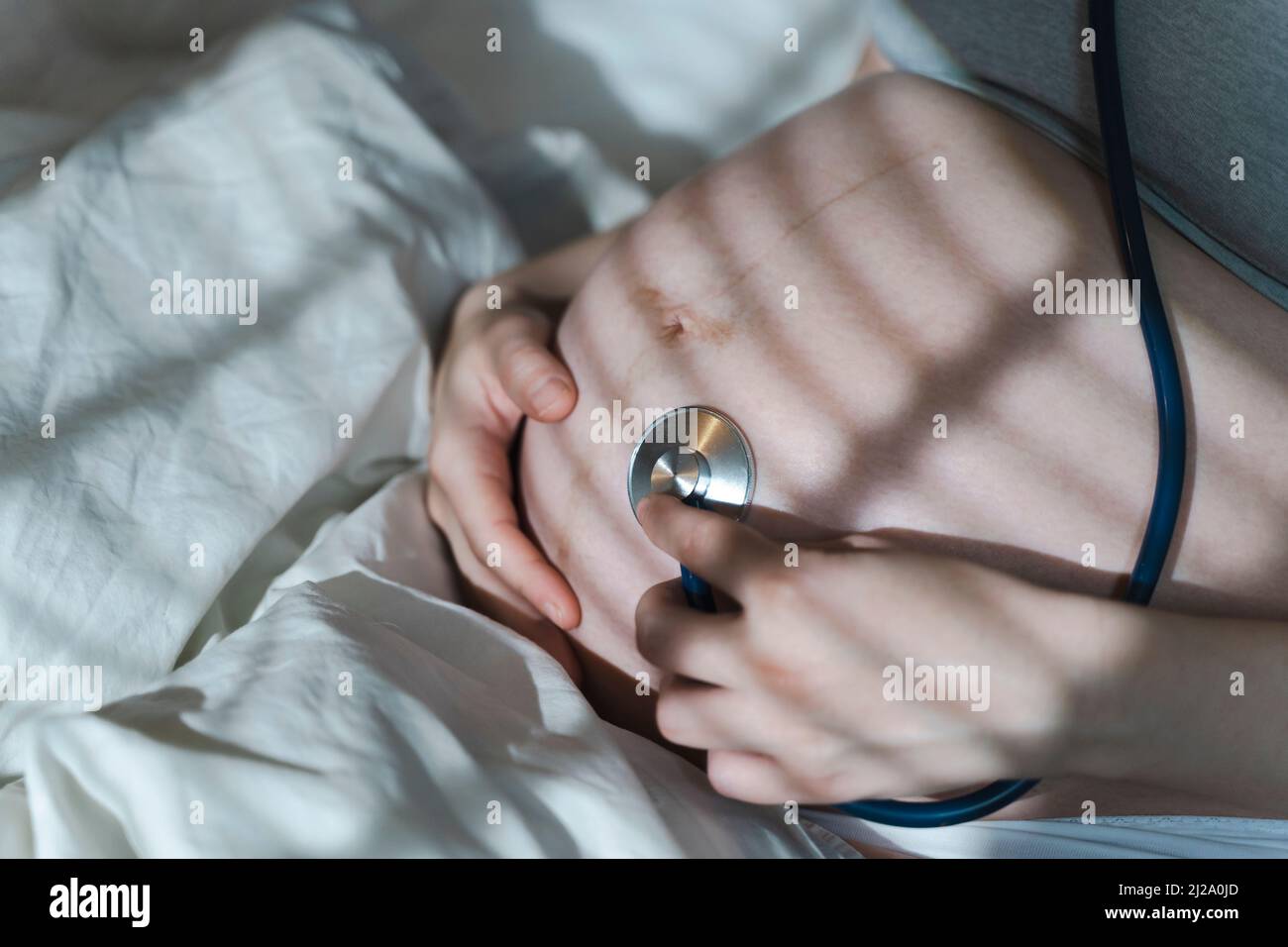 Pregnant woman listens to the baby heartbeat and movements with a stethoscope or fetoscope or Pinard Horn. Prenatal fetal health, anxiety, fear concept. High quality photo Stock Photo
