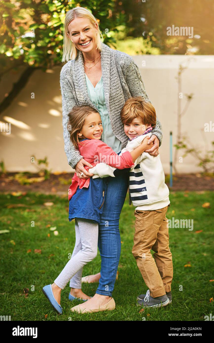 Hugs filled with an abundance of love. Portrait of two adorable siblings hugging their mother outside. Stock Photo
