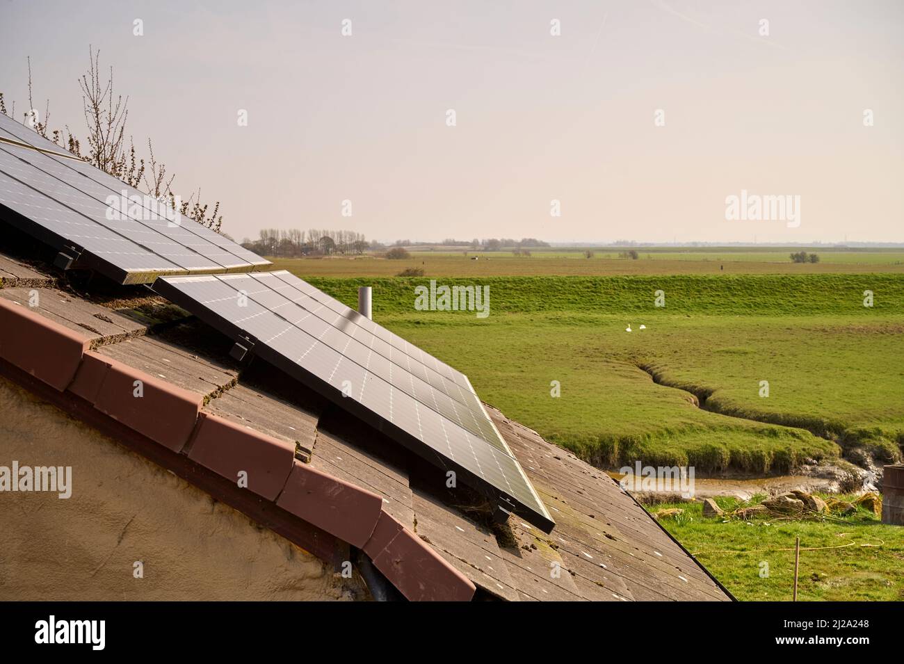 Solar panels on roof of house overlooking river flood plain Stock Photo