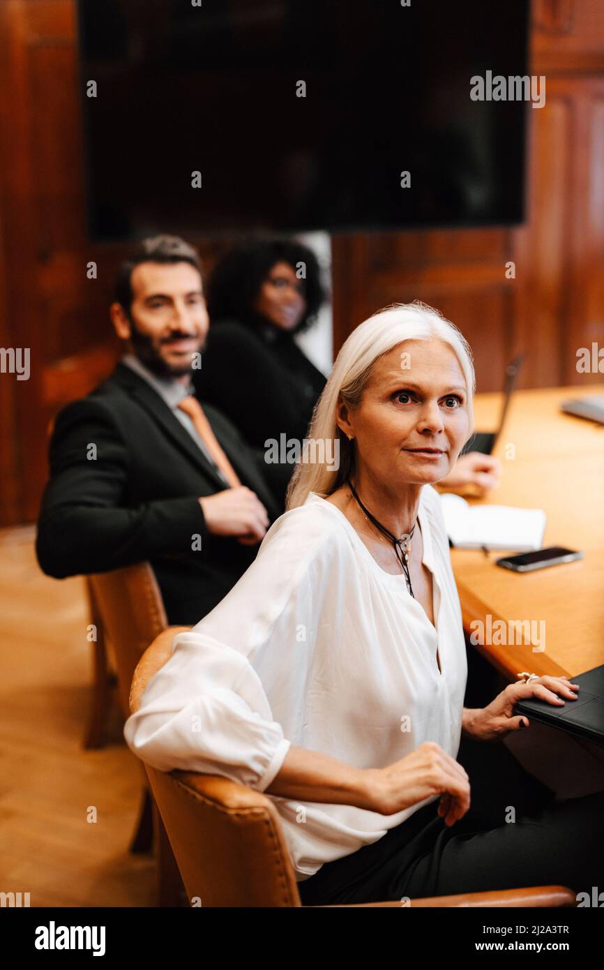 Multiracial female and male colleagues sitting at conference table in ...