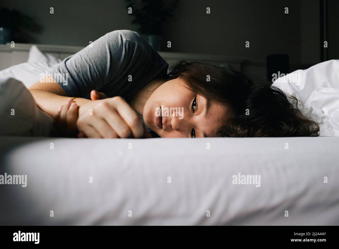 Tired woman suffering from mental health disorder lying on bed alone at home Stock Photo