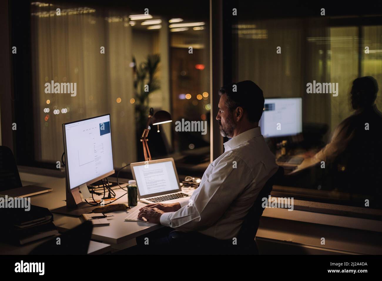 Businessman typing on computer keyboard while working in office at night Stock Photo