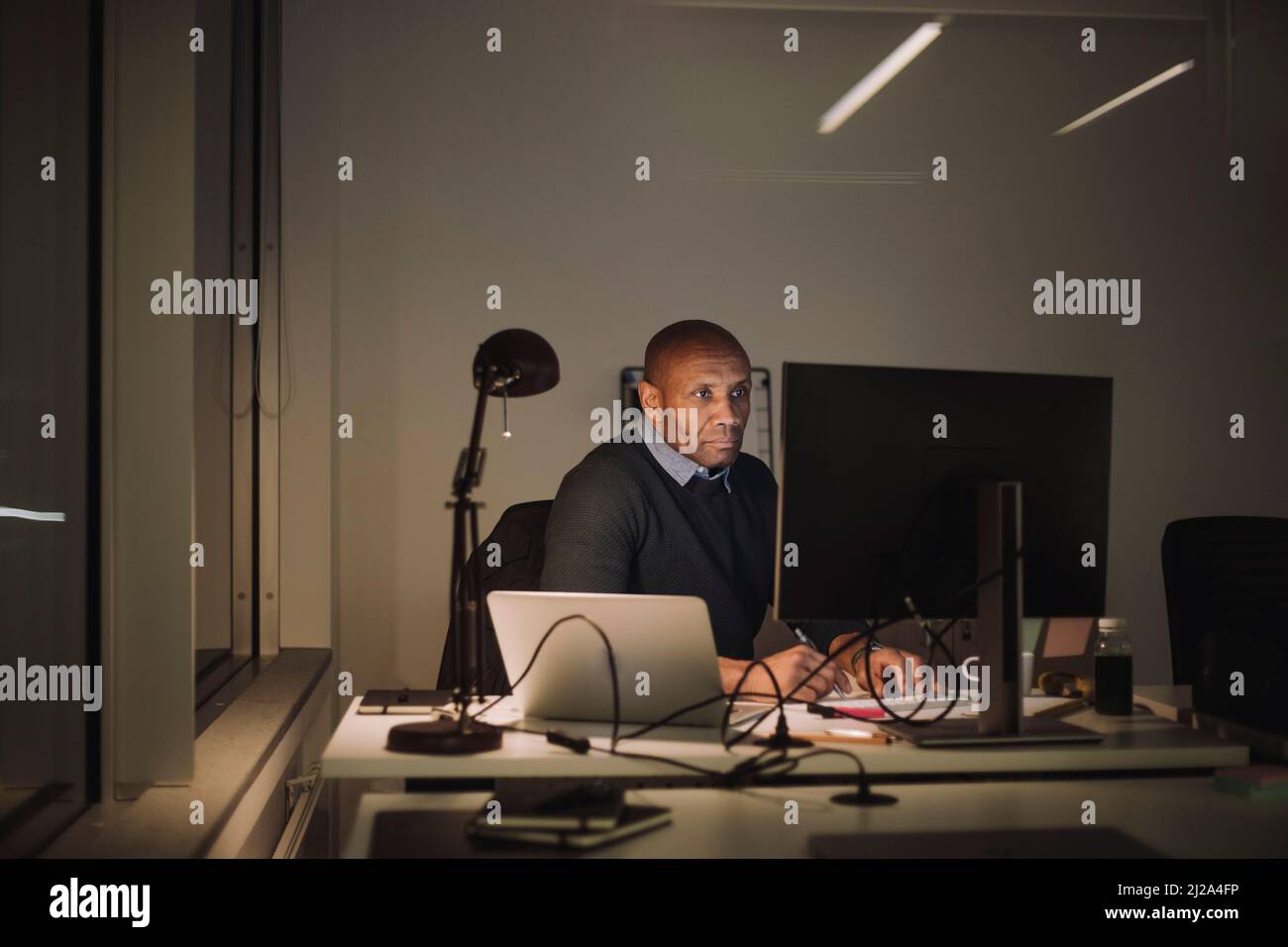 Dedicated businessman using computer while working overtime in office at night Stock Photo