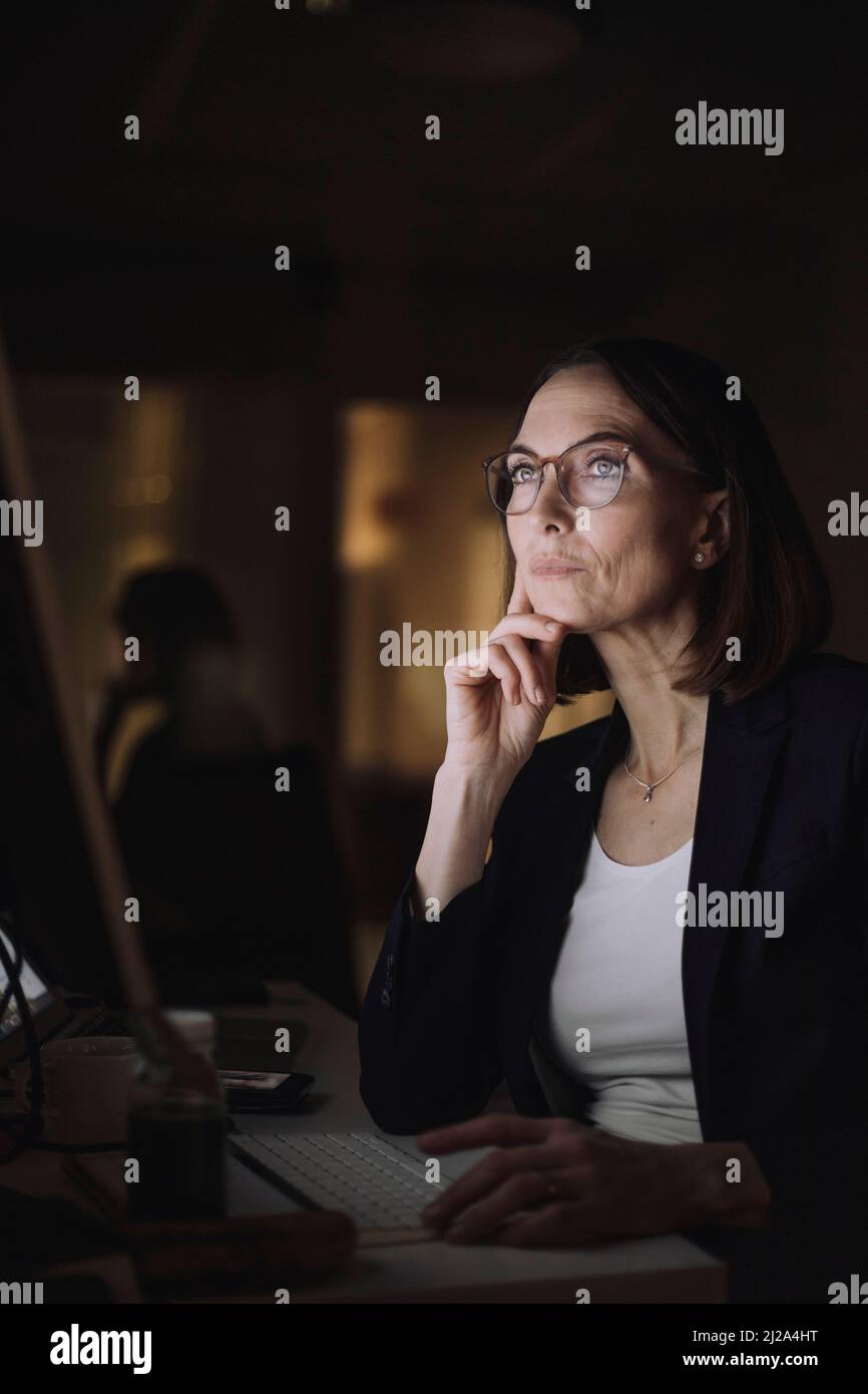 Mature businesswoman with eyeglasses working on computer at work place Stock Photo
