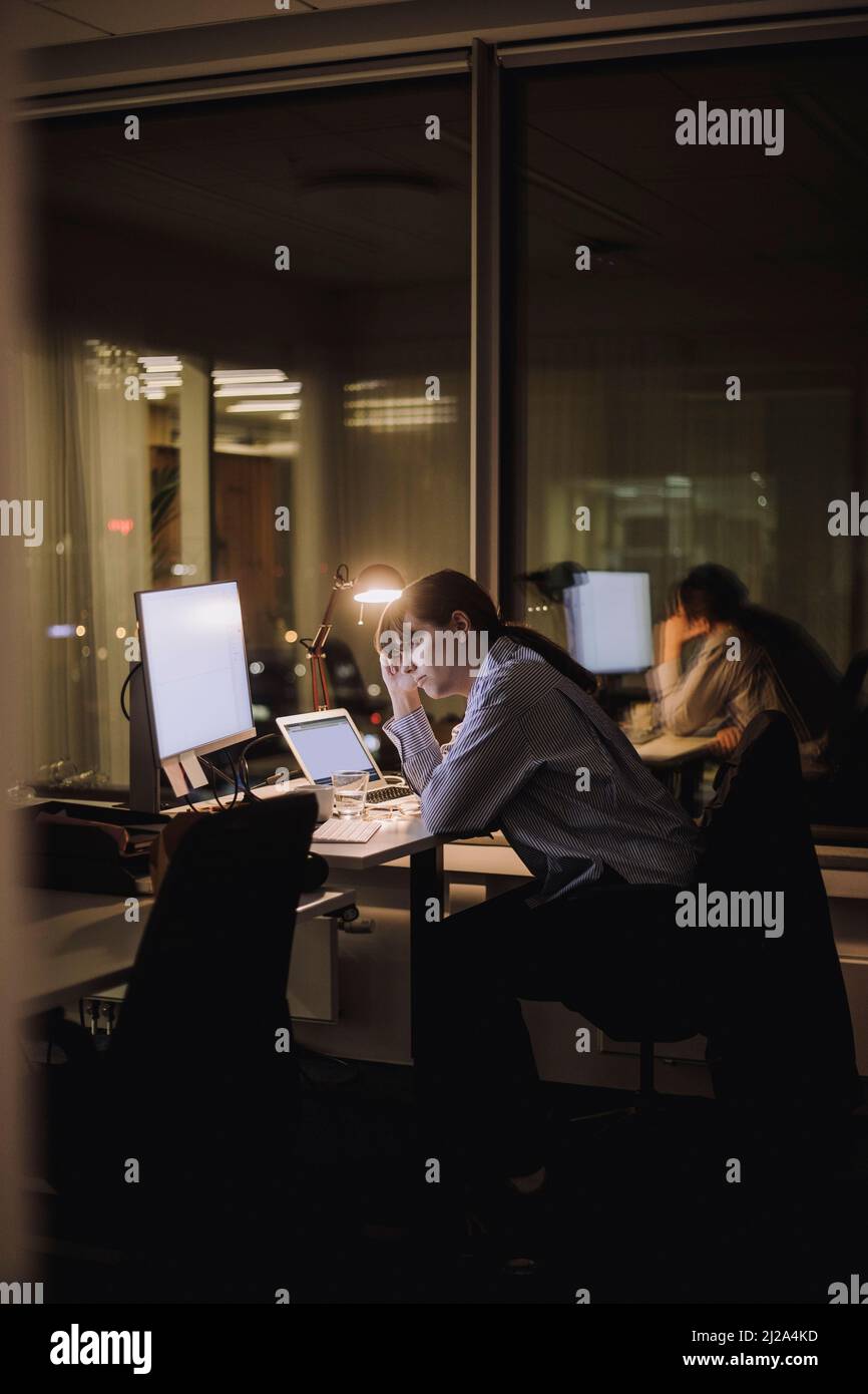 Exhausted businesswoman working overtime in office at night Stock Photo
