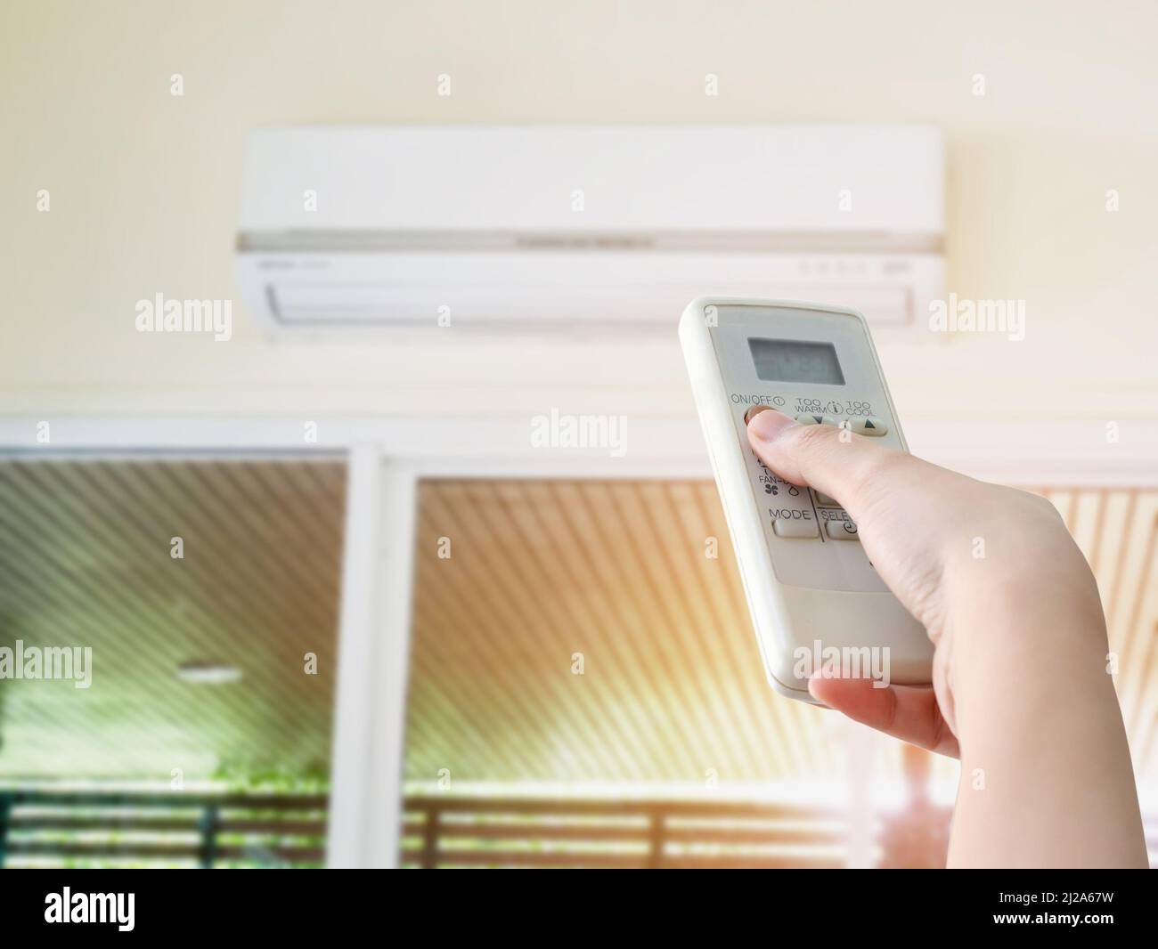Hand hold remote control directed on the air conditioner Stock Photo