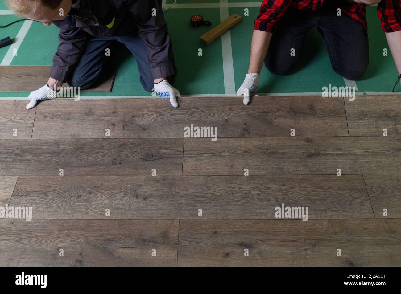 A worker hands knocking on a laminate connecting the panels with a Lock Click Stock Photo