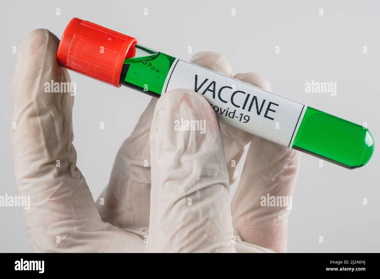 Vacuum tube with a sample of Covid19 vaccine of green color in the