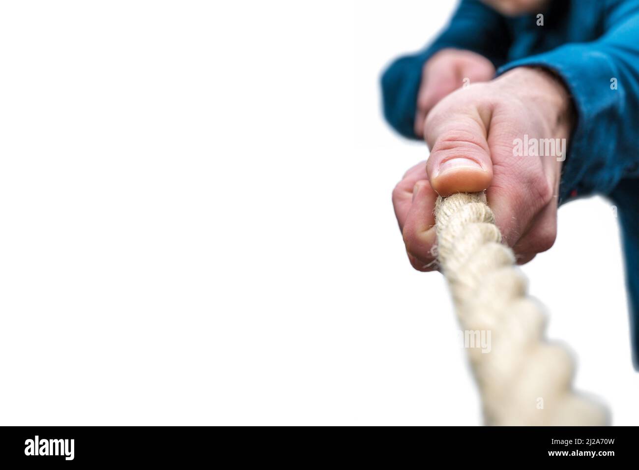 Man in blue shirt pulls thick rope against white background with copy ...