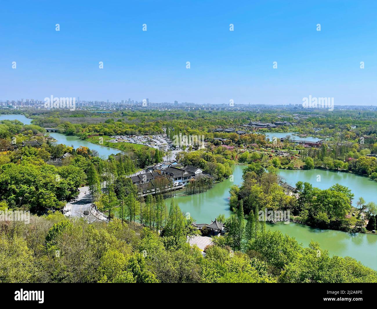 An Aerial view of a small lake surrounded by green trees and black roof ...