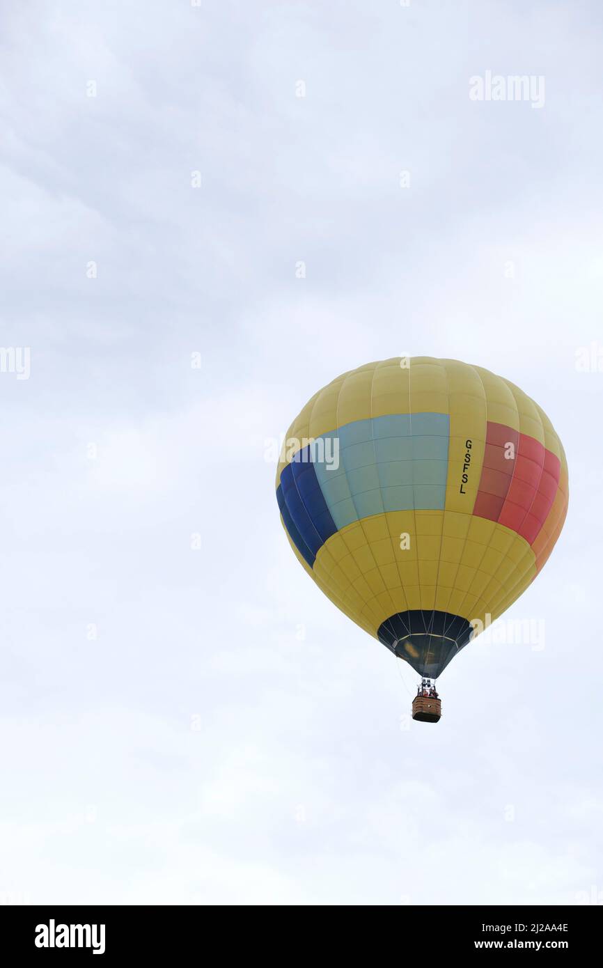 A large hot air ballon carrying passengers takes off into a bright sky. Stock Photo