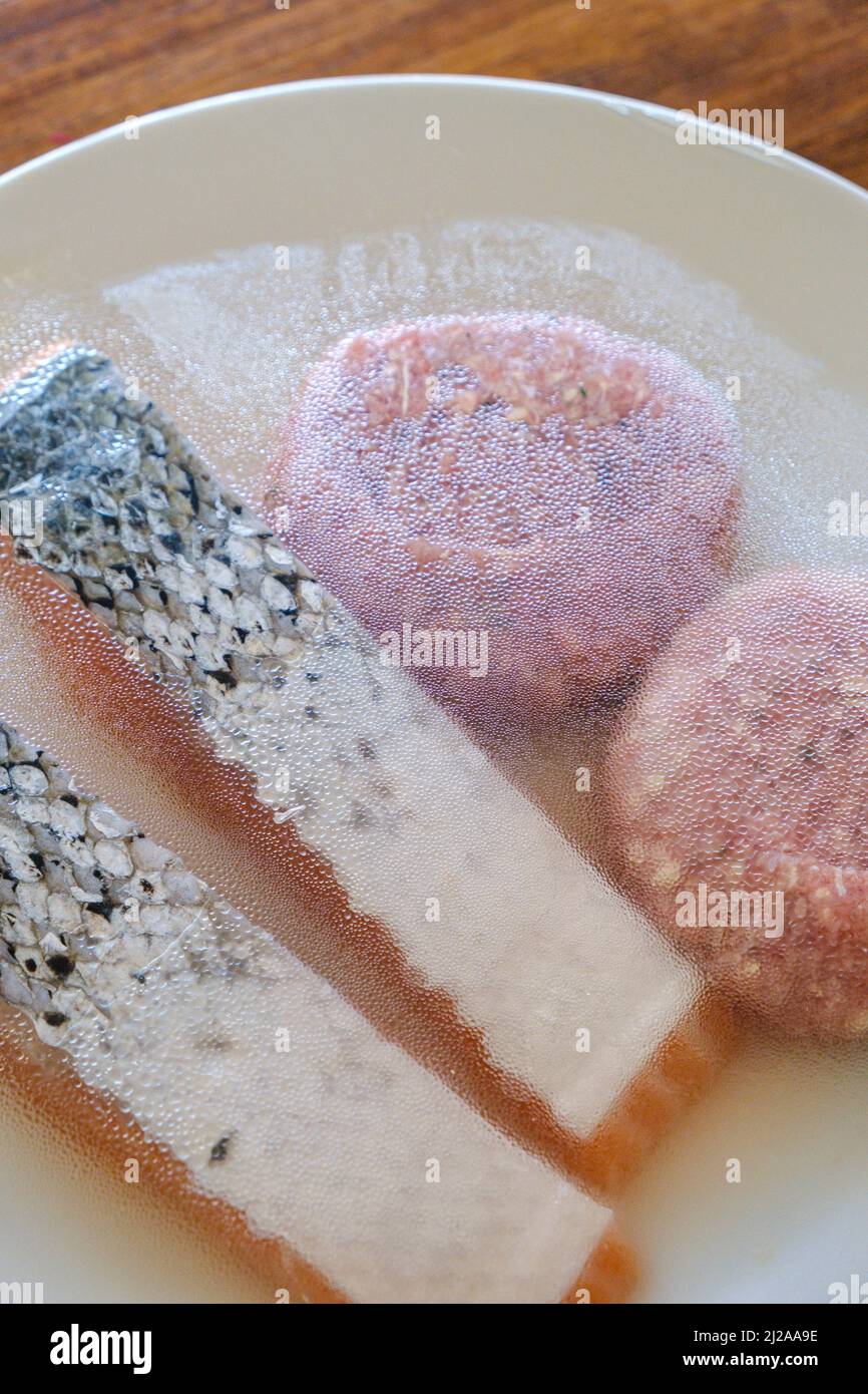 A plate of uncooked food, inclduing salmon fillets and beef burgers ready for a barbecue. Stock Photo