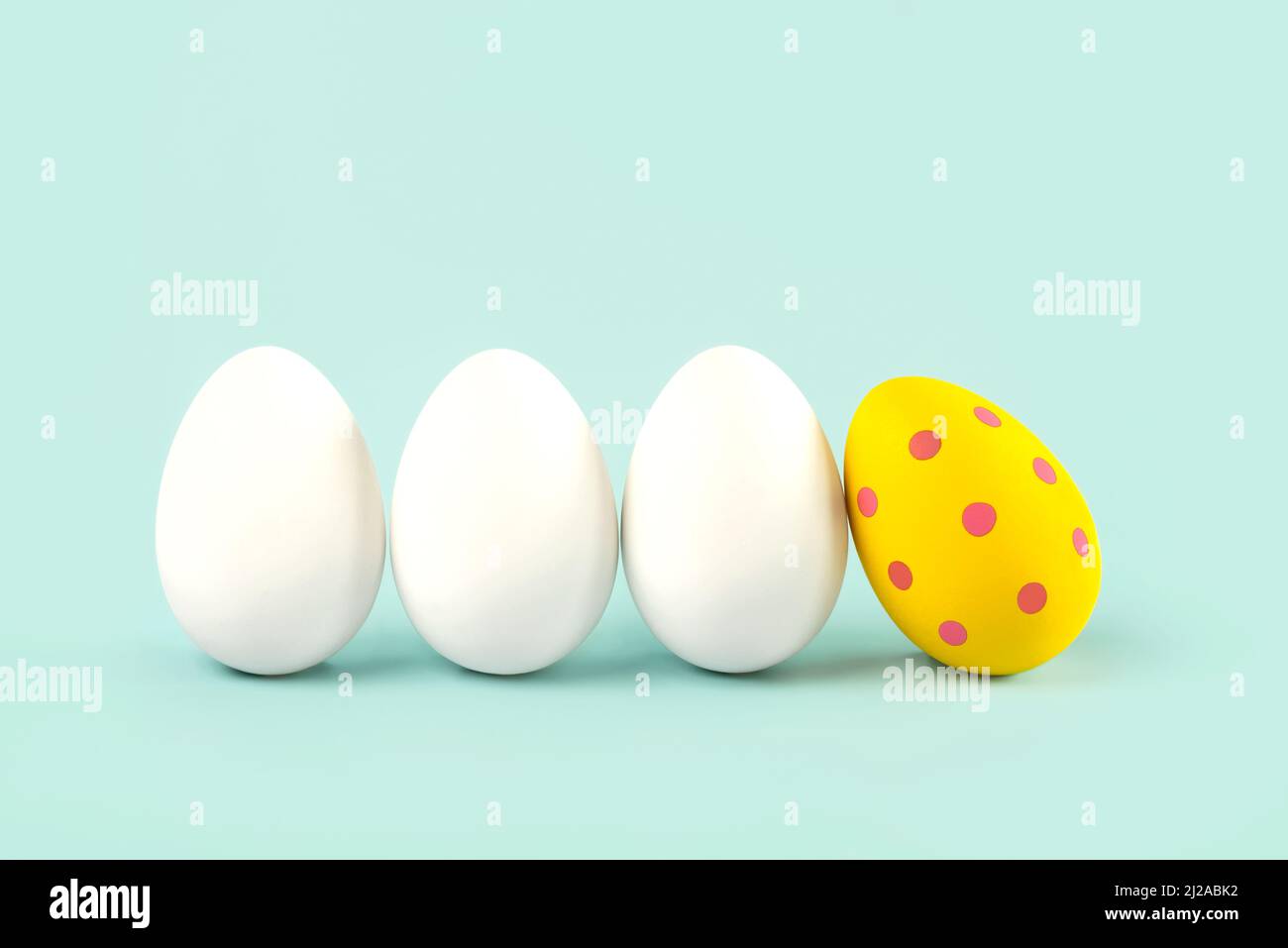 Happy Easter. Close-up of three white eggs and easter painted egg over blue background Stock Photo