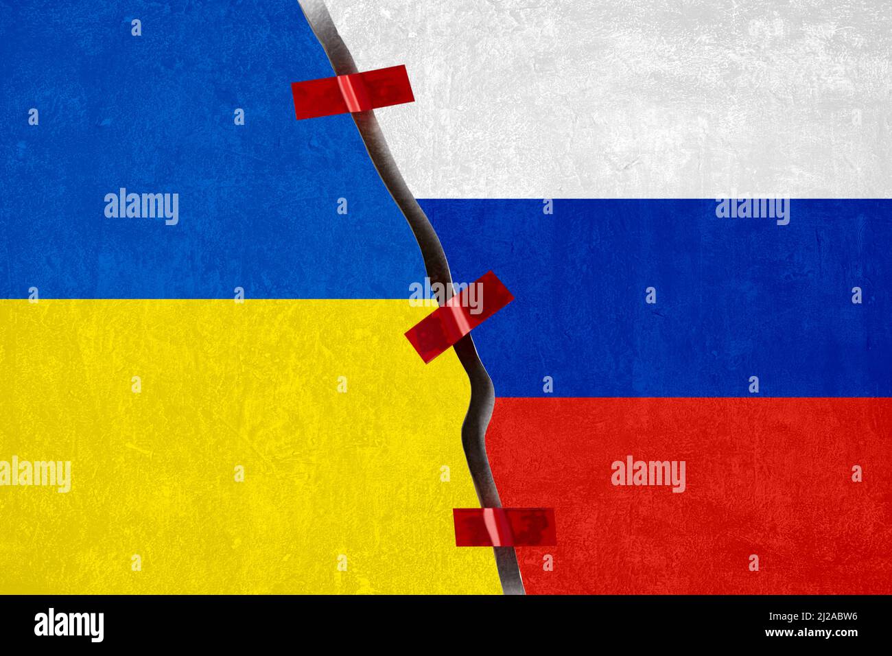 Ukrainian and Russian flags against the background of a torn surface of a concrete wall Stock Photo