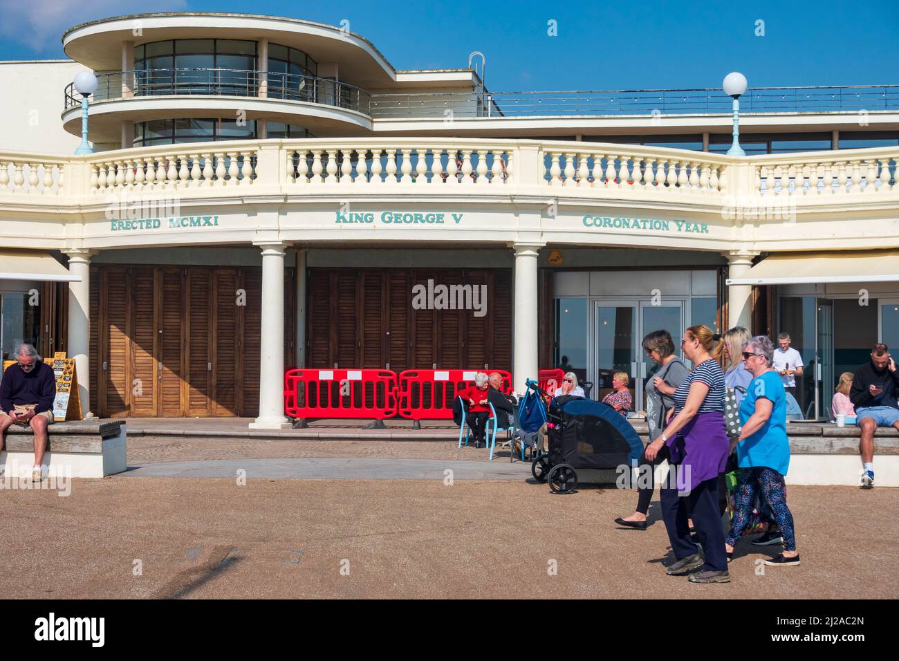Warm Early Spring day on Bexhill seafront, visitors look at the stores under the De La Warr Pavilion, East Sussex, UK Stock Photo