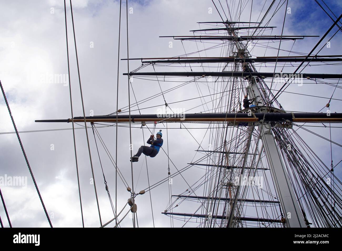 A climber uses the breeches buoy technique to descend from the rigging
