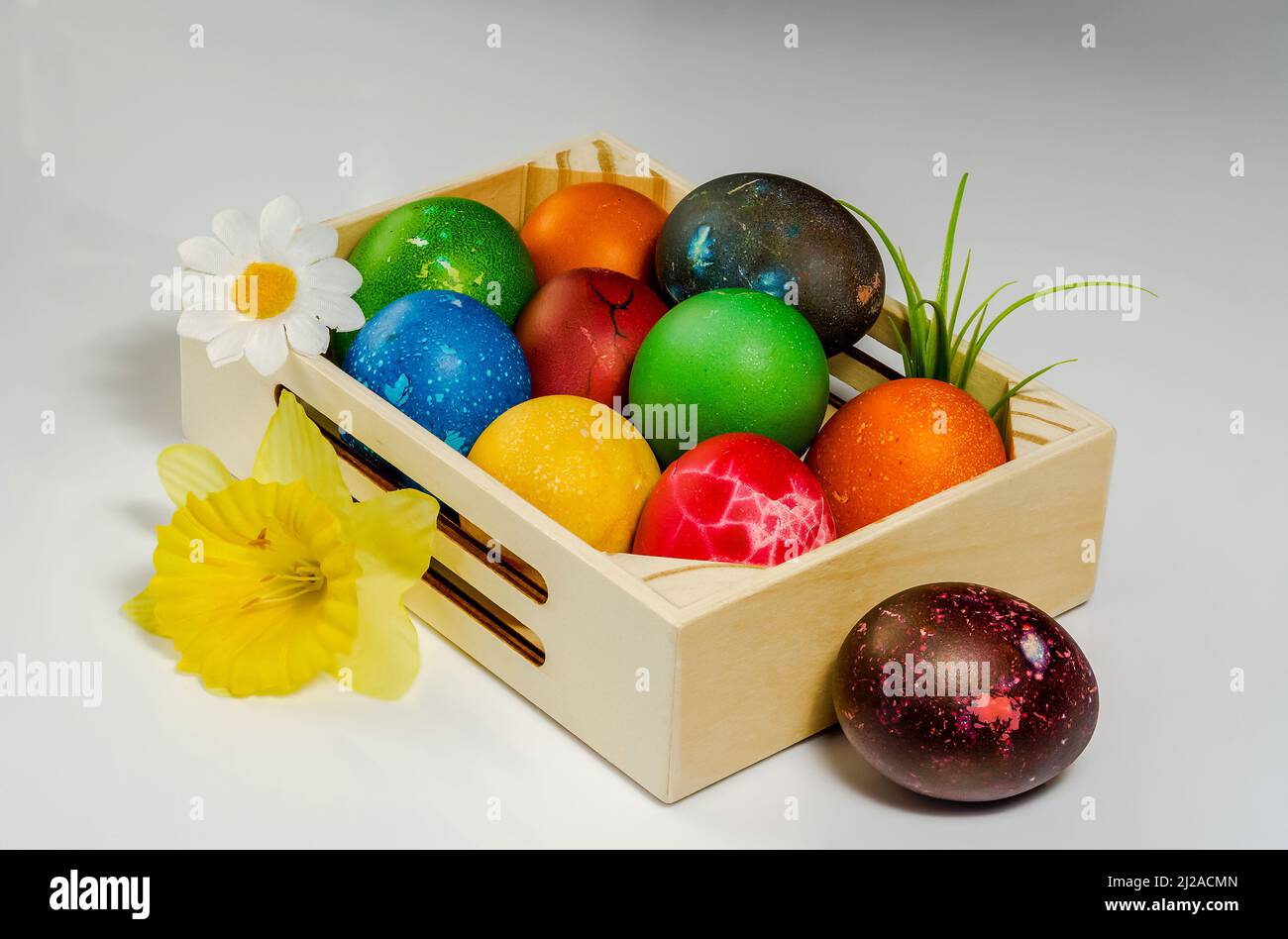 Easter composition, colorful, hand-painted eggs arranged in a small wooden box, still life on a light background, flowers Stock Photo