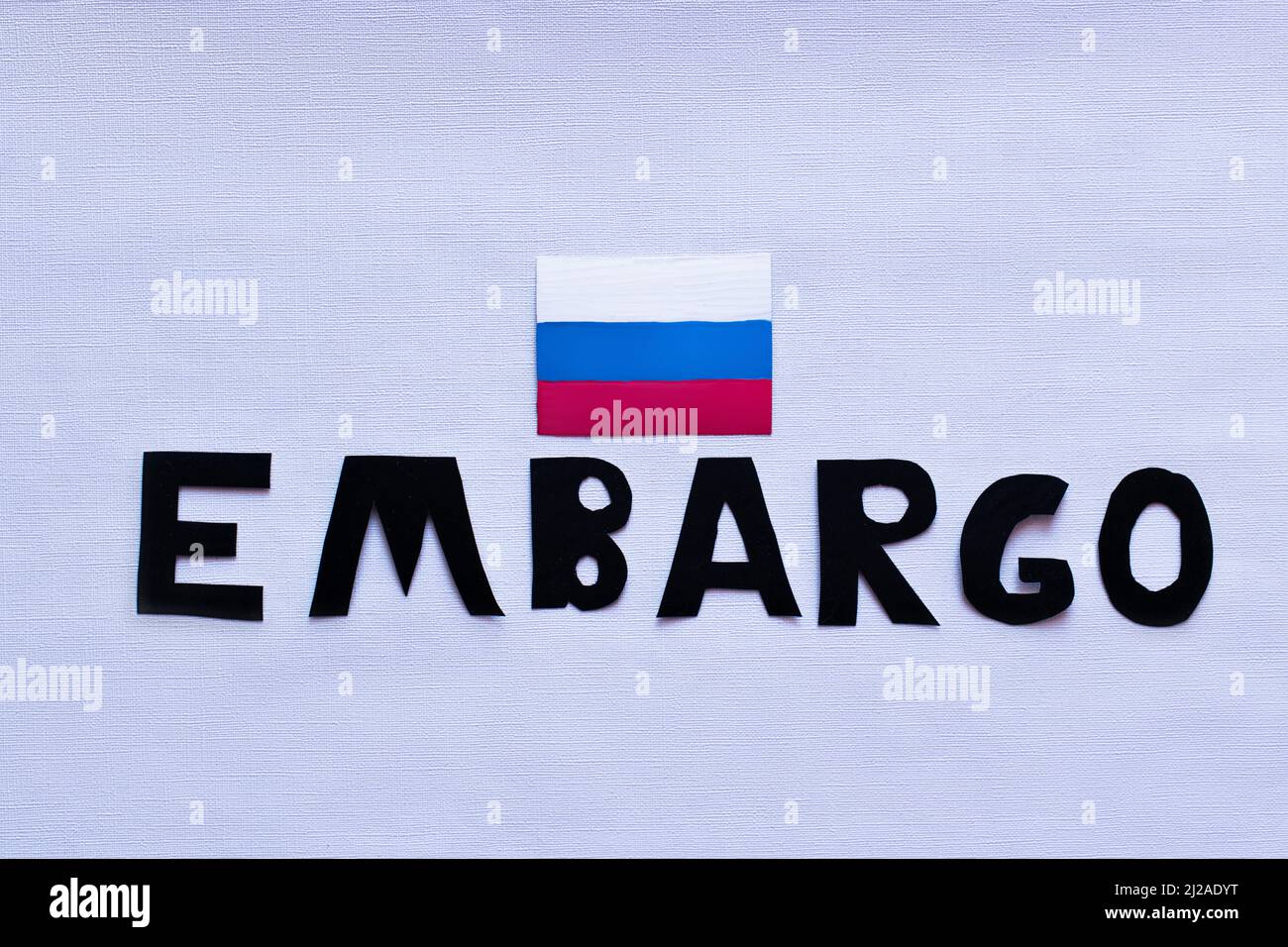 Top view of russian flag and embargo lettering on white background, war