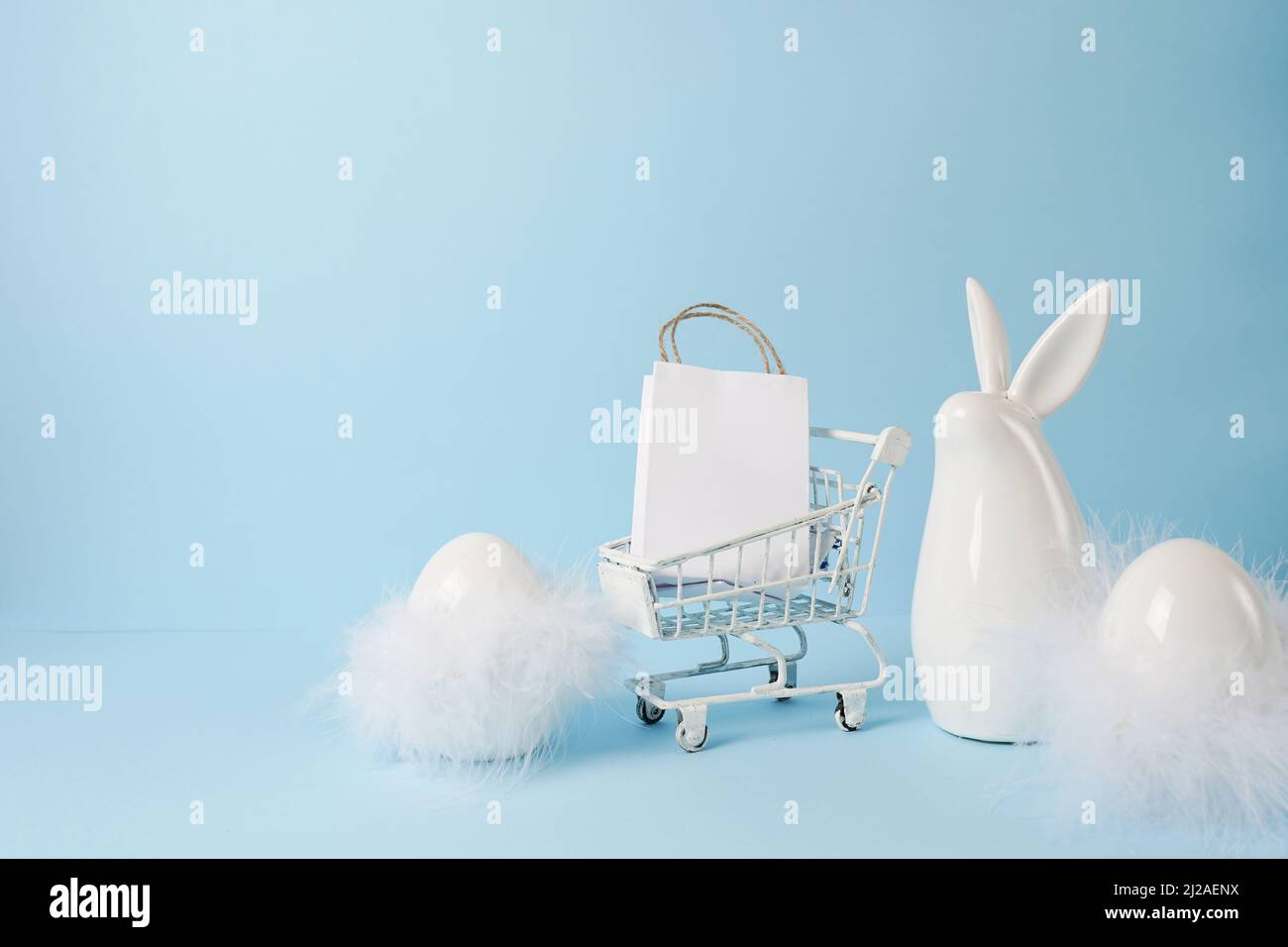 https://c8.alamy.com/comp/2J2AENX/white-easter-bunny-with-shopping-cart-and-easter-eggs-on-blue-background-2J2AENX.jpg