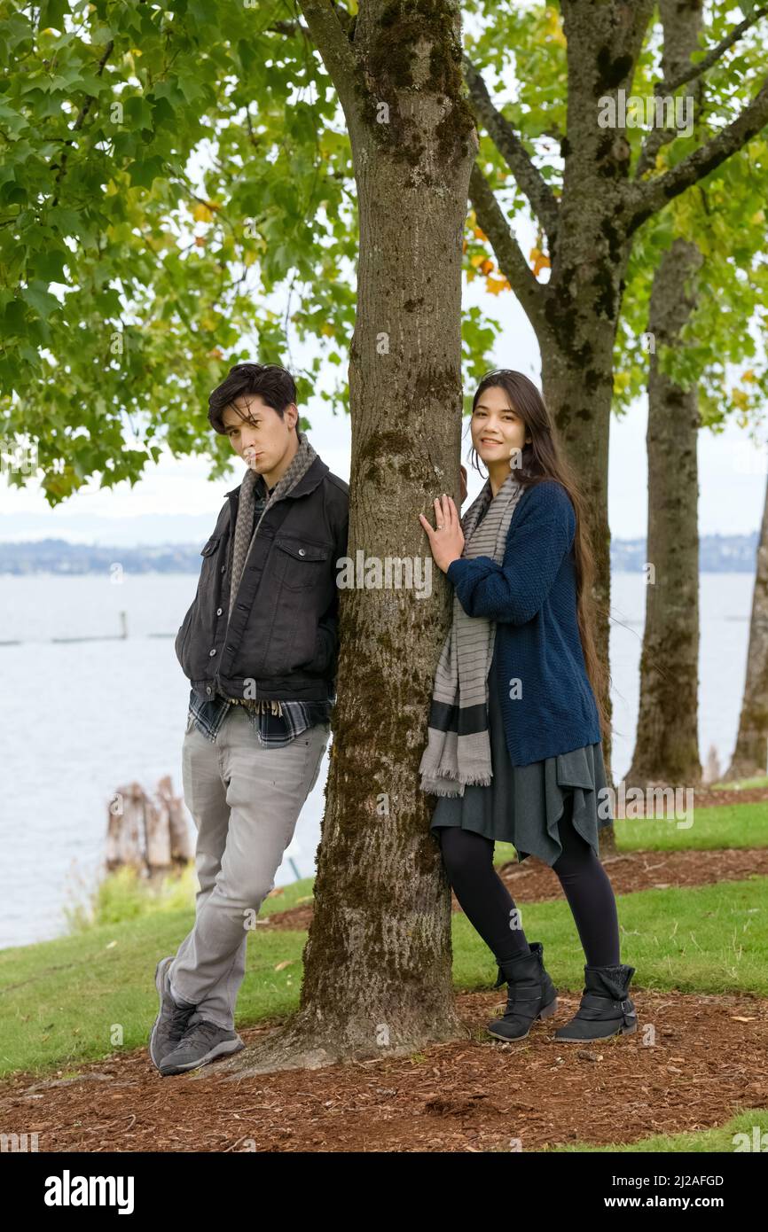 Young  biracial  couple standing together by lake in park Stock Photo