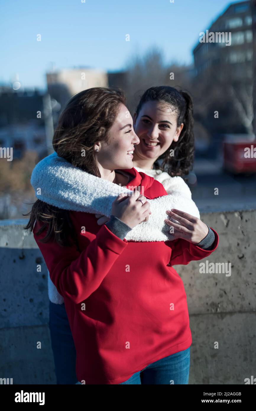 Close-up photo of laughing woman friends hugging each other on city ...