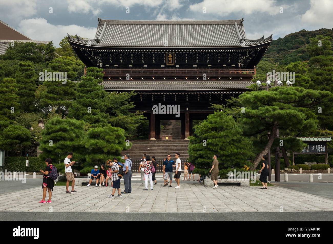 Horizontal frontal view of a group of tourists in front of the Chion-in Buddhist Temple entrance in Gion, Southern Higashiyama, Kyoto, Japan Stock Photo