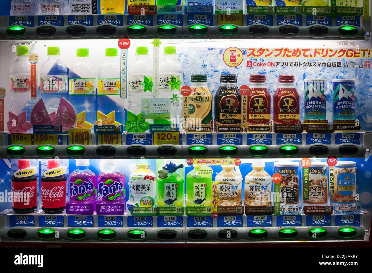 Horizontal close-up view of an illuminated and colorful Japanese soda vending machine at night Stock Photo