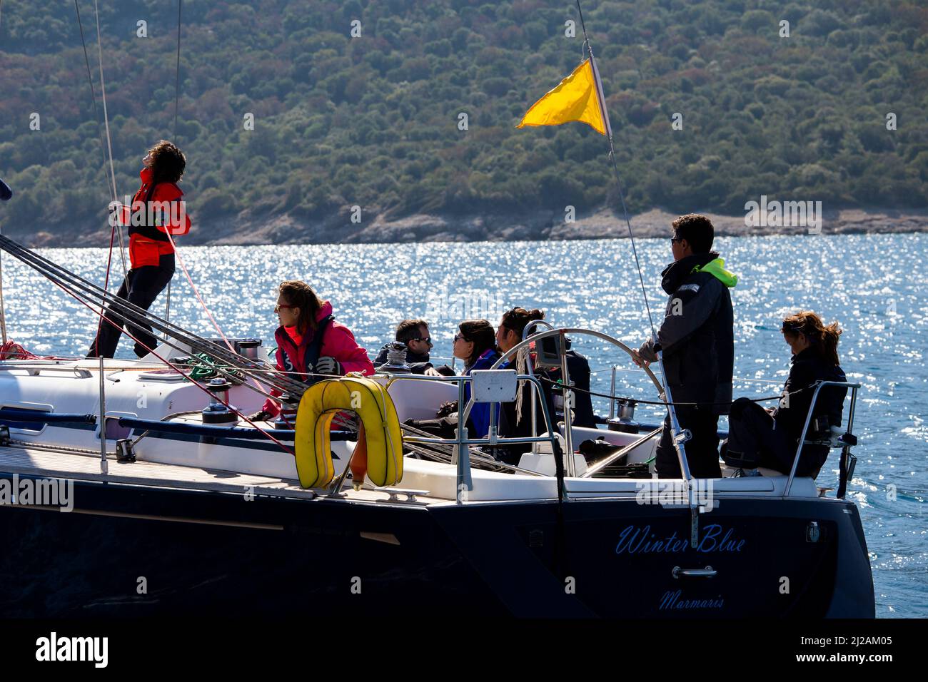 Bodrum, Mugla, Turkey - 02.25.2022: Teamwork and team spirit on deck of ship yacht sailing on blue waters of Aegean Sea. Sailboats sail in wind Stock Photo