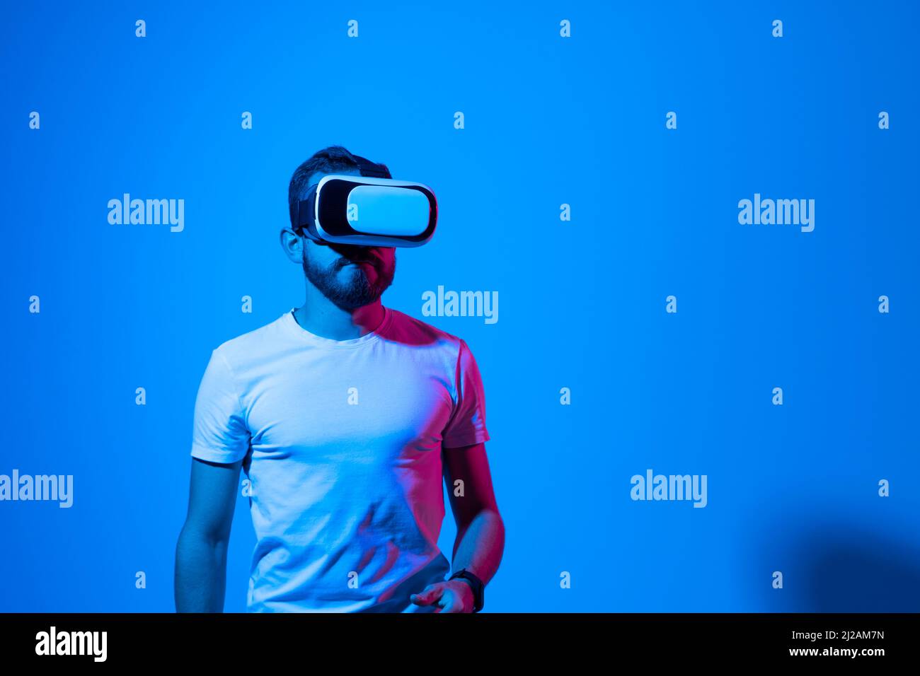 Bearded young man wearing virtual reality goggles and interacting with ...