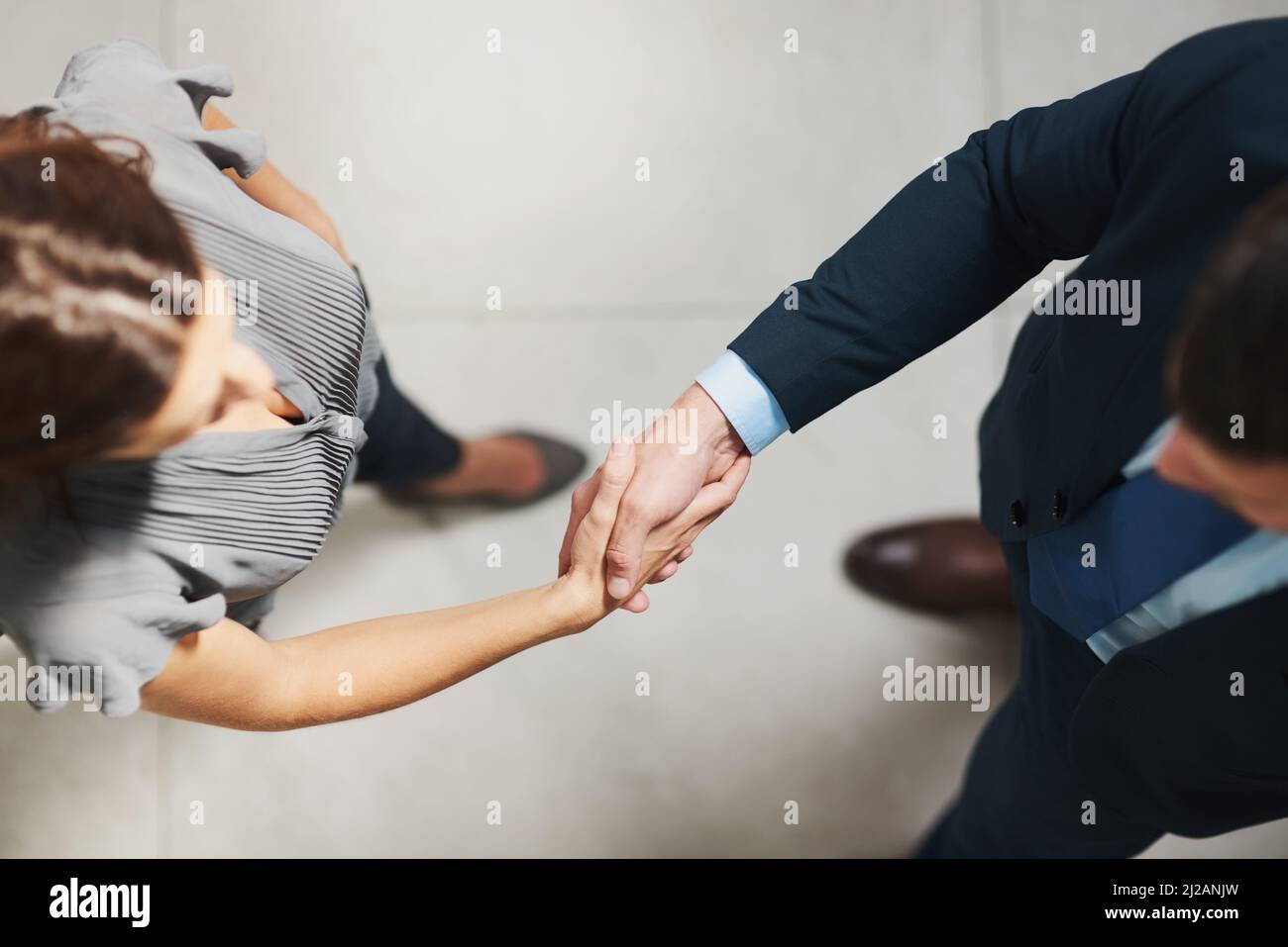 Well accomplish some great things together. High angle shot of two businesspeople shaking hands in an office. Stock Photo