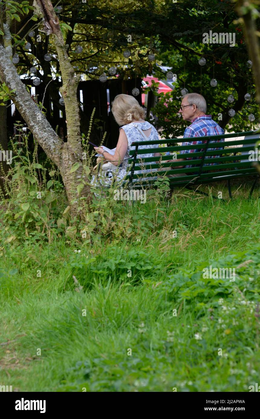 older couple sitting relaxing in woodland area Stock Photo