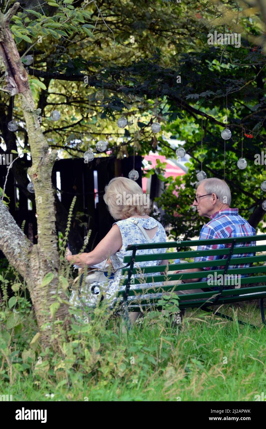 older couple sitting together on garden bench Stock Photo