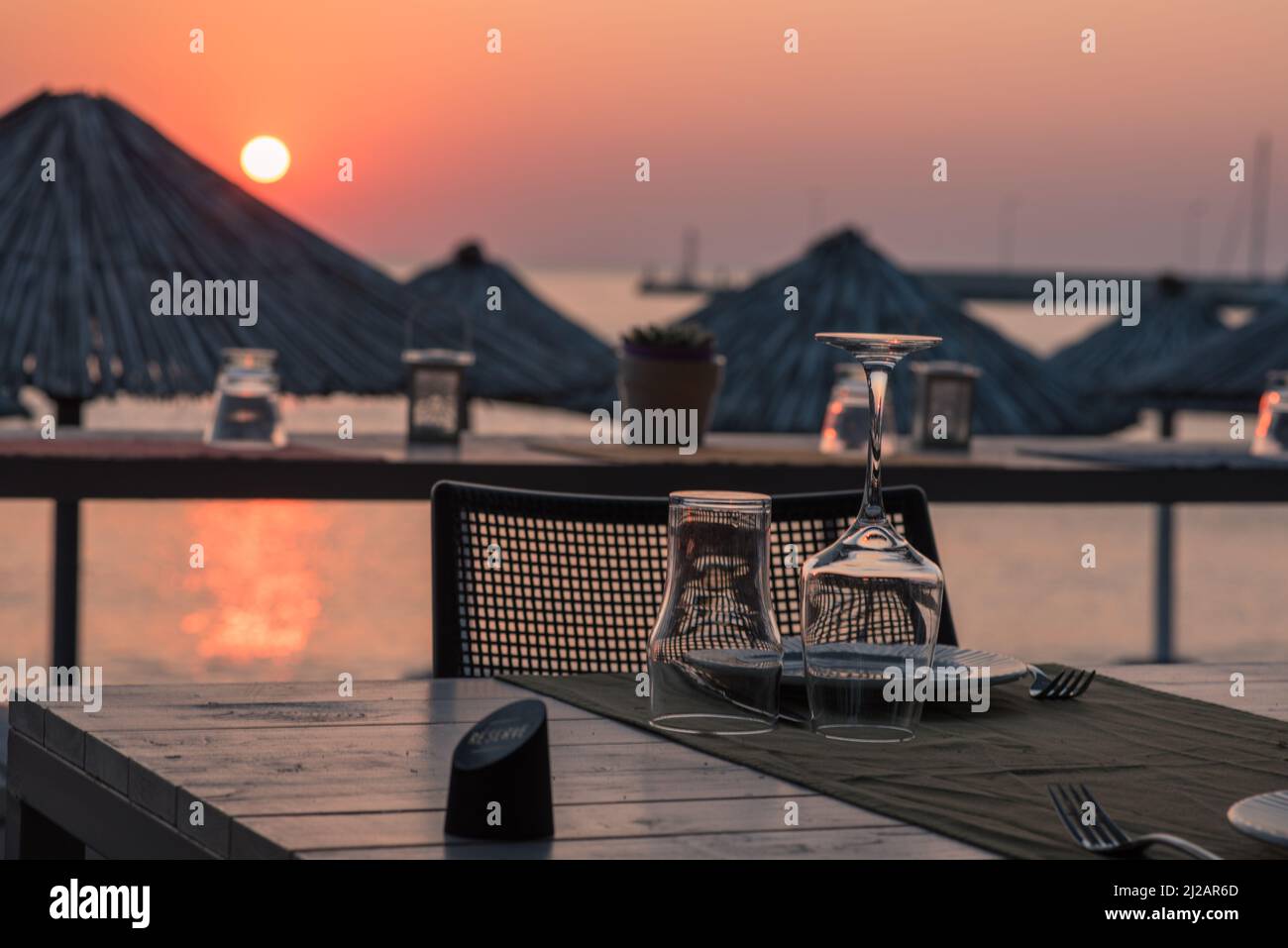 Sunset at a greek restaurant in front of the sea. Reservation table. Stock Photo