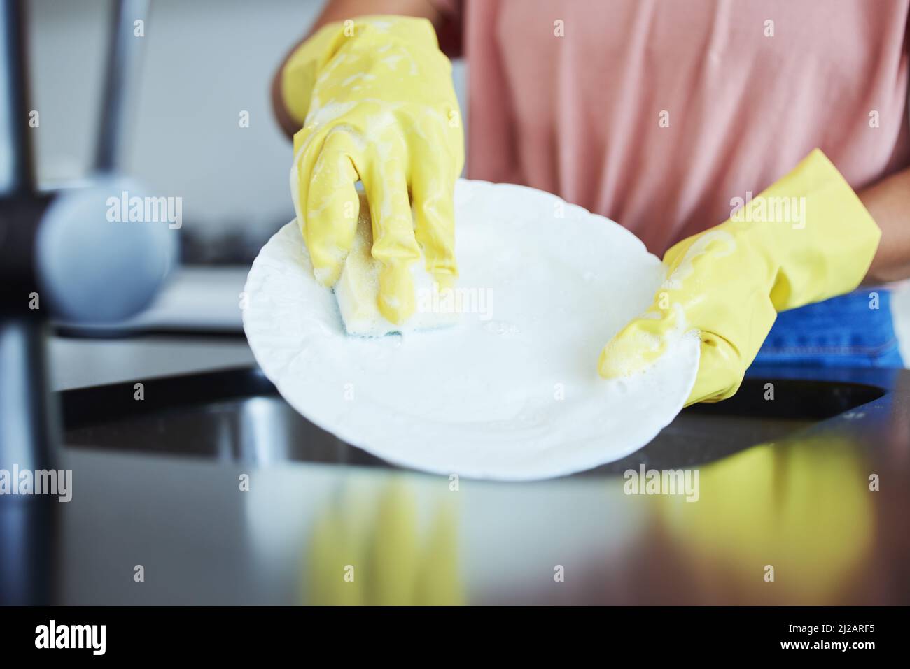 I love seeing clean dishes. Shot of a woman washing dishes in her kitchen. Stock Photo