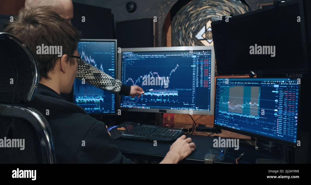 Two man traders on stock exchange discussing charts of falling and