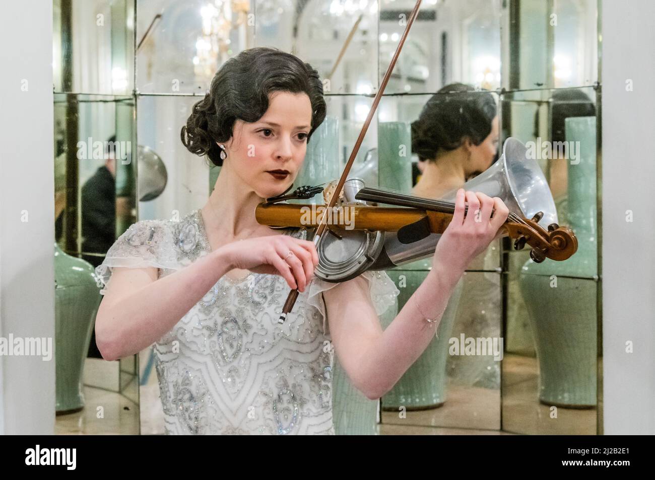 London, UK. 31 Mar 2022. Rebecca Smith plays the Stroh violin in a replica vintage dress - The Savoy combines forces with Alex Mendham and his orchestra to raise funds for Ukraine. In the 1920s and 1930s the Savoy Orpheans were a household name, and for this charitable collaboration, the orchestra will become ‘The New Savoy Orpheans', and create an exclusive recording in the hotel. They play in the hotel's Lancaster Ballroom, to record a medley of pieces that represent the finest melodies of the Jazz Age with the intention of raising valuable funds for the Disasters Emergency Committee. Cr Stock Photo