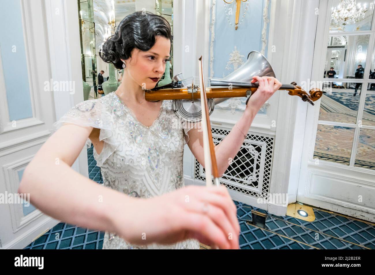 London, UK. 31 Mar 2022. Rebecca Smith plays the Stroh violin in a replica vintage dress - The Savoy combines forces with Alex Mendham and his orchestra to raise funds for Ukraine. In the 1920s and 1930s the Savoy Orpheans were a household name, and for this charitable collaboration, the orchestra will become ‘The New Savoy Orpheans', and create an exclusive recording in the hotel. They play in the hotel's Lancaster Ballroom, to record a medley of pieces that represent the finest melodies of the Jazz Age with the intention of raising valuable funds for the Disasters Emergency Committee. Cr Stock Photo