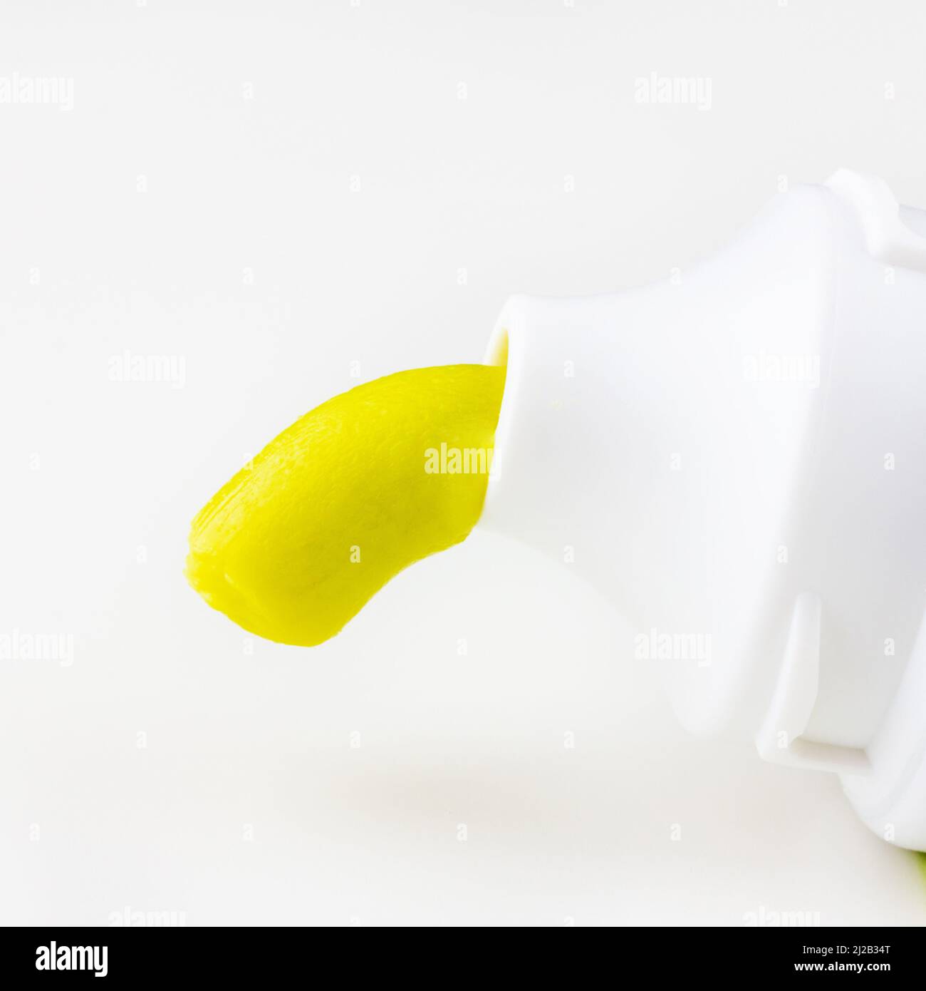 green toothpaste is squeezed out of a tube of toothpaste on a white background closeup Stock