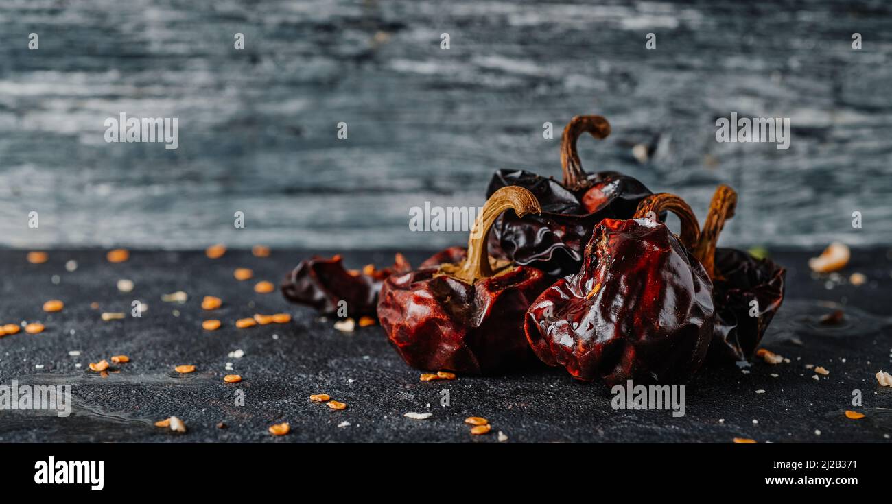 some spanish dried nora peppers, used in many traditional spanish recipes, on a textured stone surface, in a panoramic format to use as web banner Stock Photo