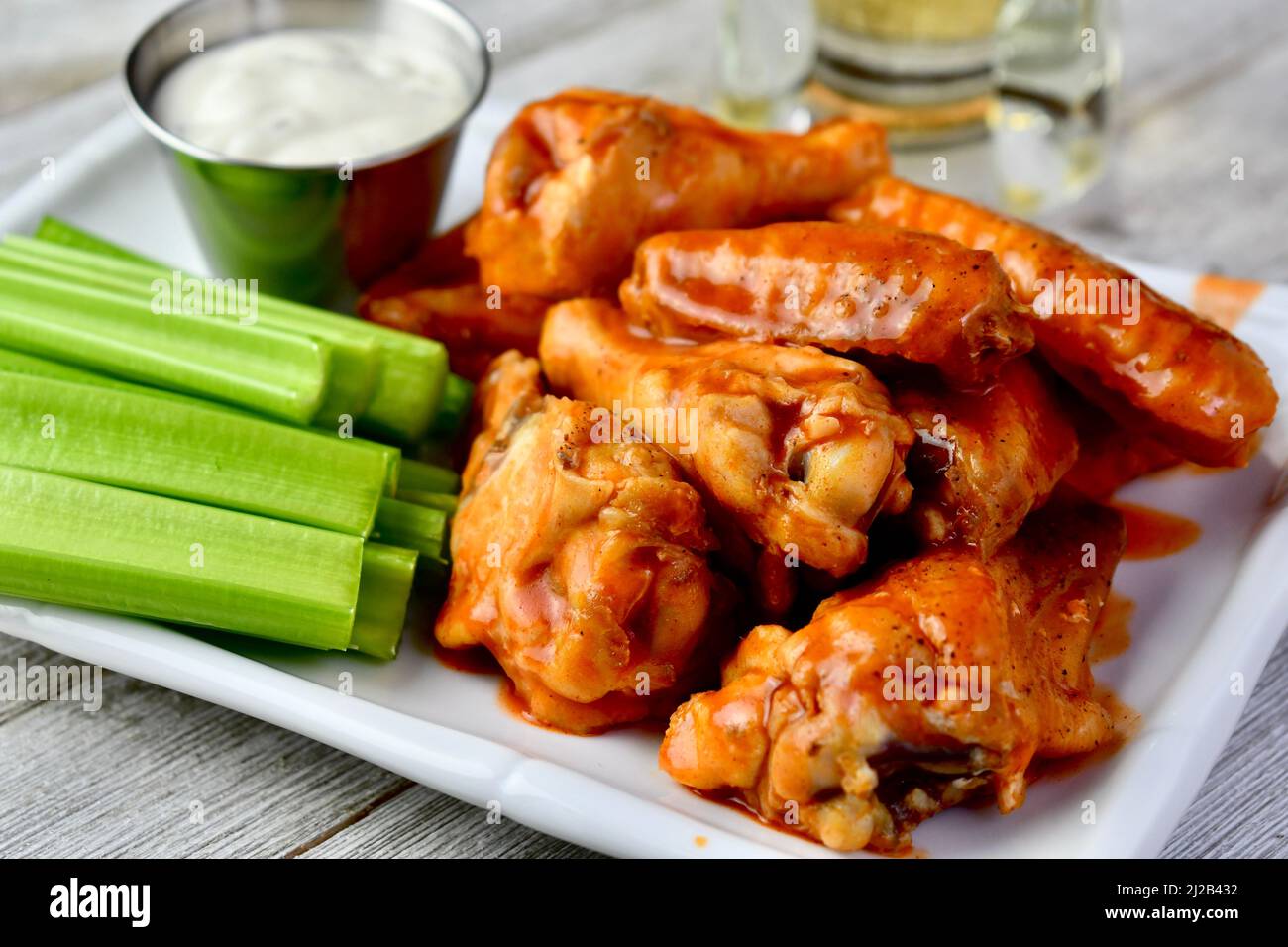 Buffalo wings with celery sticks and ranch dressing on a white