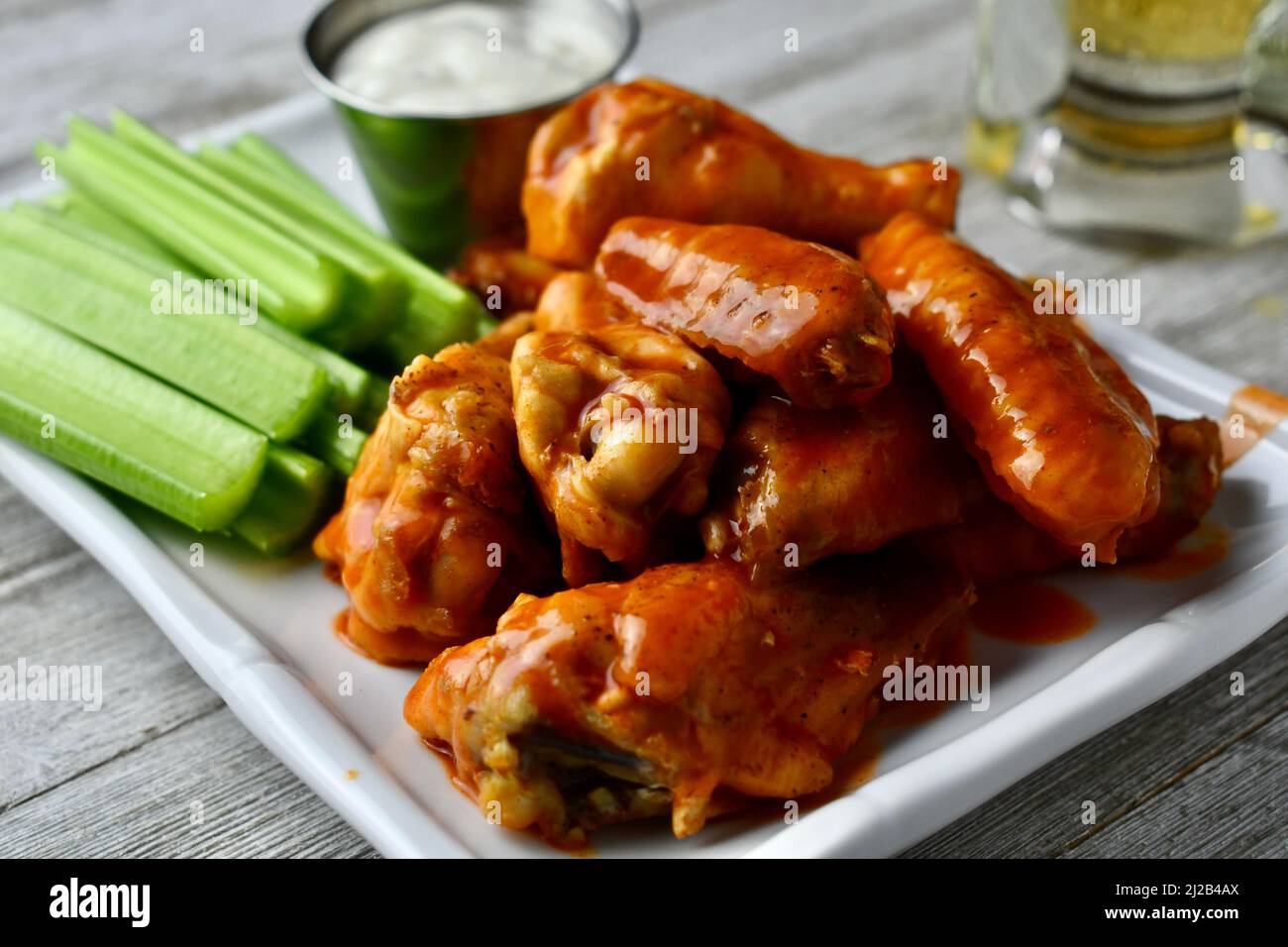 Buffalo wings with celery sticks and ranch dressing on a white