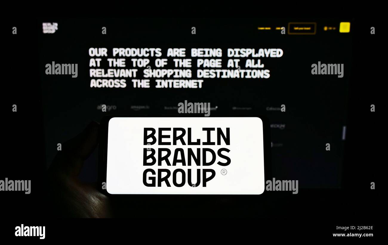 Person holding smartphone with logo of company Chal-Tec GmbH (Berlin Brands Group) on screen in front of website. Focus on phone display. Stock Photo