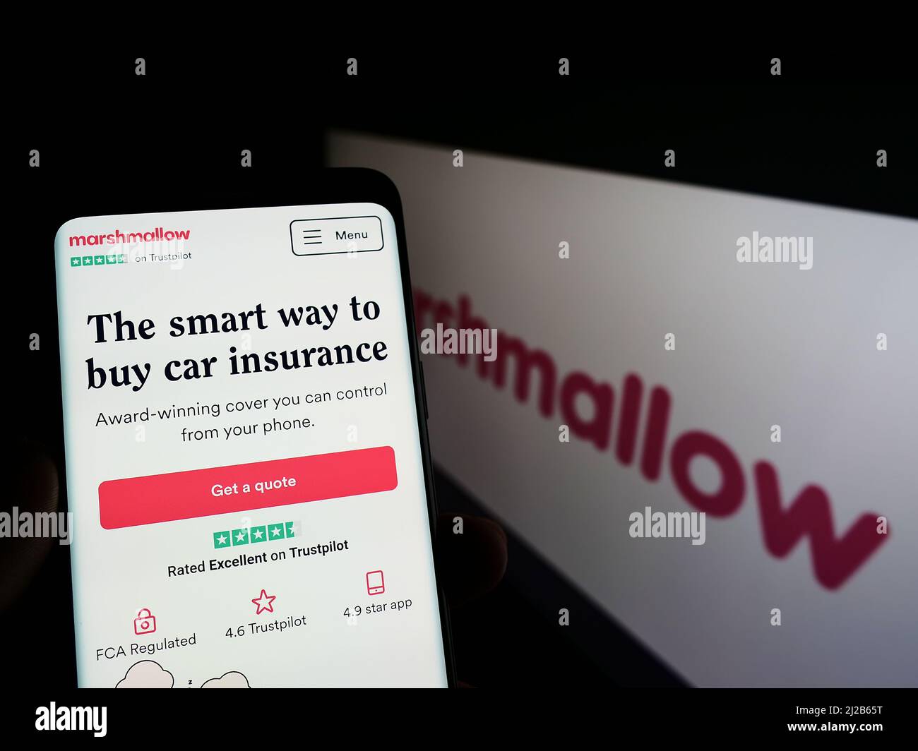 Person holding cellphone with webpage of company Marshmallow Financial Services Limited on screen with logo. Focus on center of phone display. Stock Photo