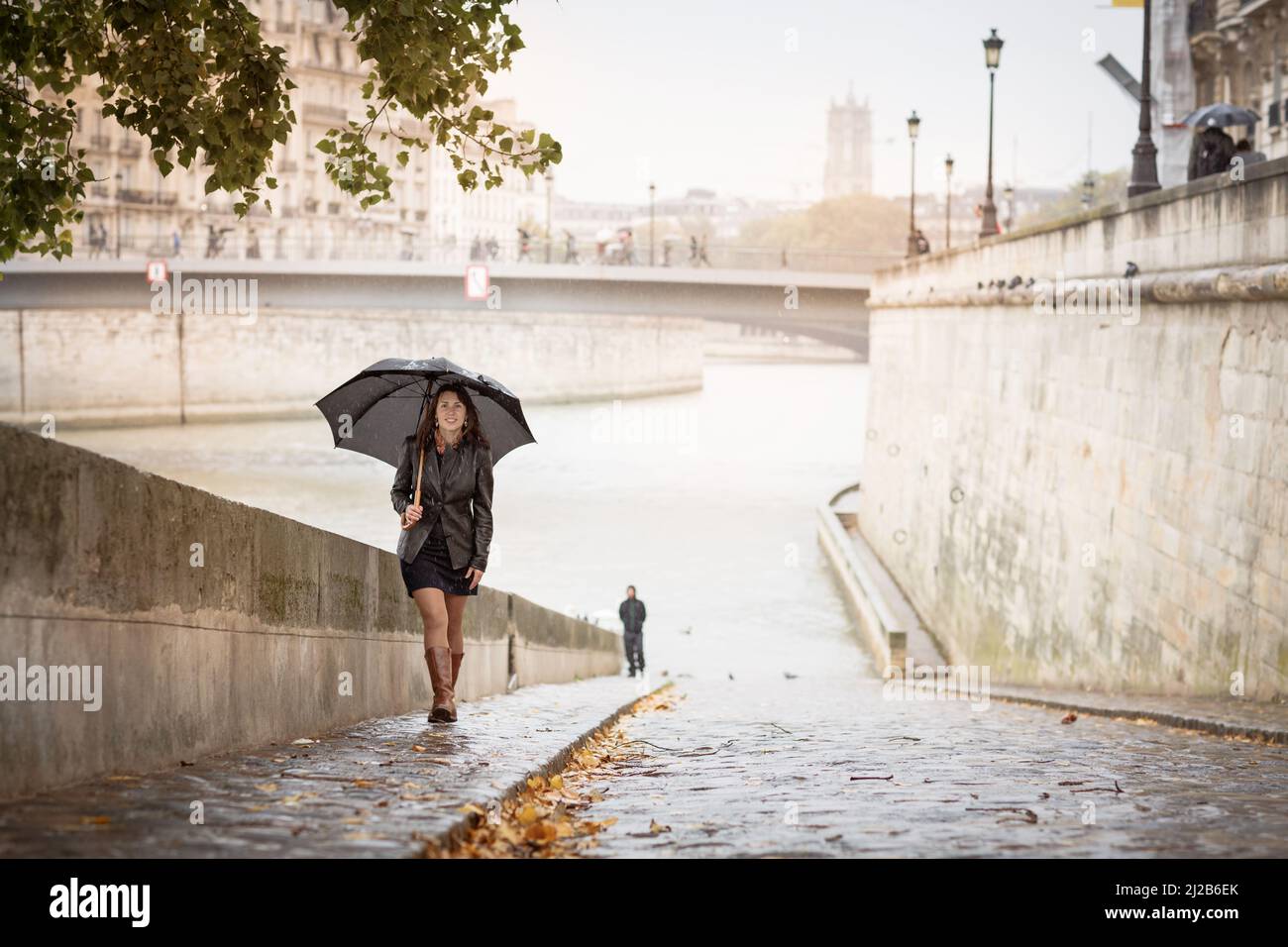 Brunette girl in a black jacket walks on the river embankment Stock ...