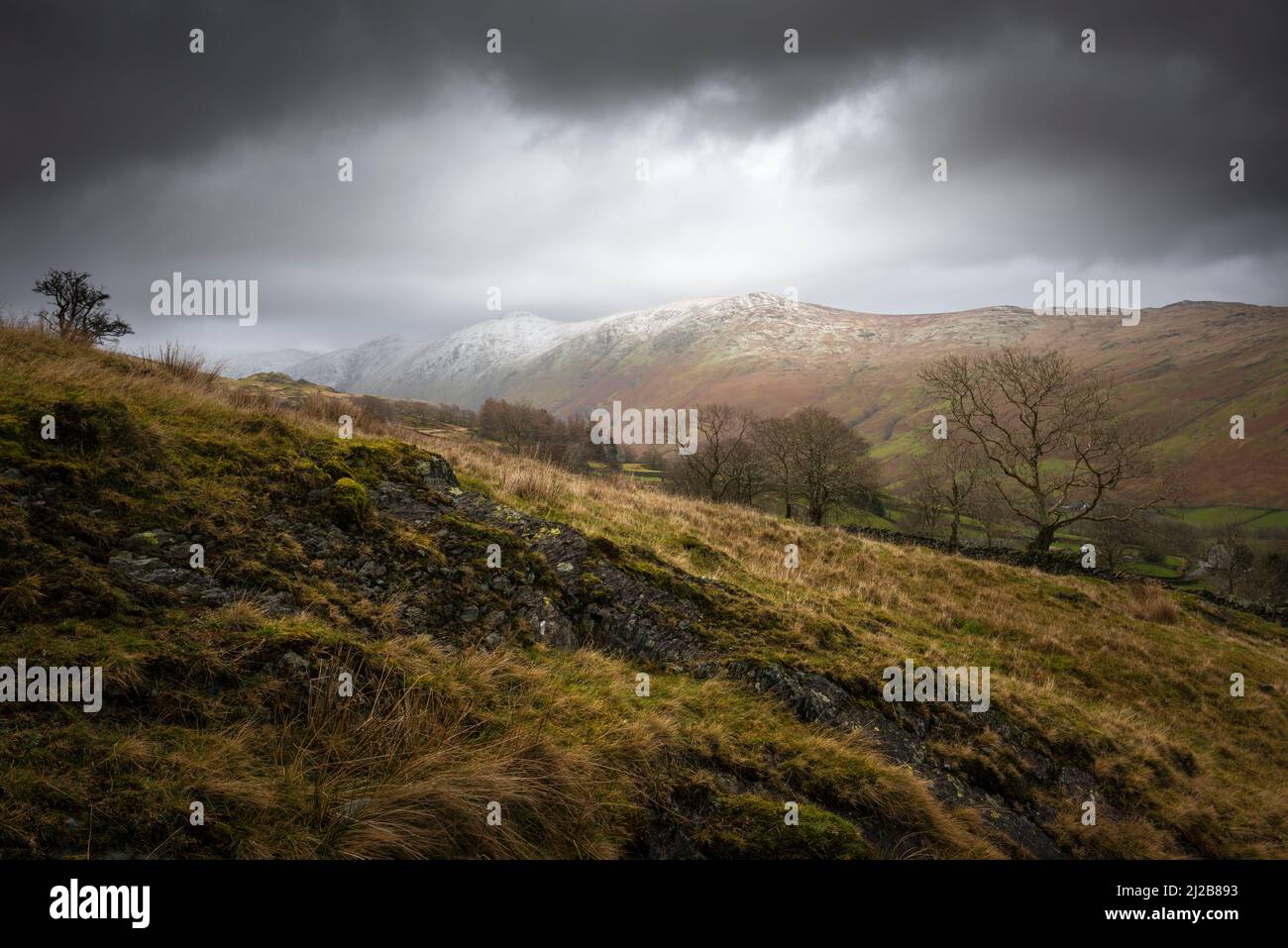The snow-capped peaks of Ill Bell and Yoke above the Trout Beck Valley from Nanny Lane in late winter in the Lake District National Park, Cumbria, England. Stock Photo