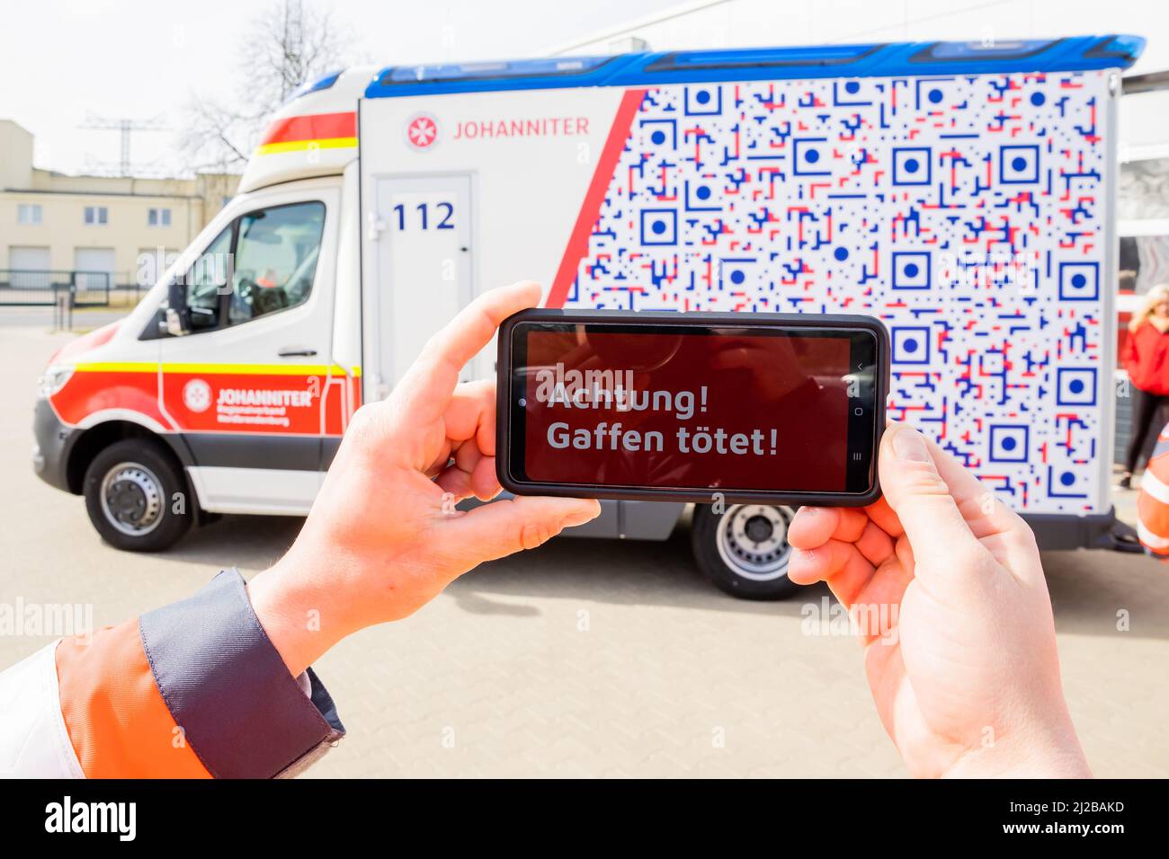 31 March 2022, Brandenburg, Angermünde: David Sohn, paramedic at  Johanniter-Unfall-Hilfe Angermünder, uses a smartphone to demonstrate how  Brandenburg's first ambulance with an "anti-gaffer design" works.  Johanniter-Unfall-Hilfe has put an ambulance ...