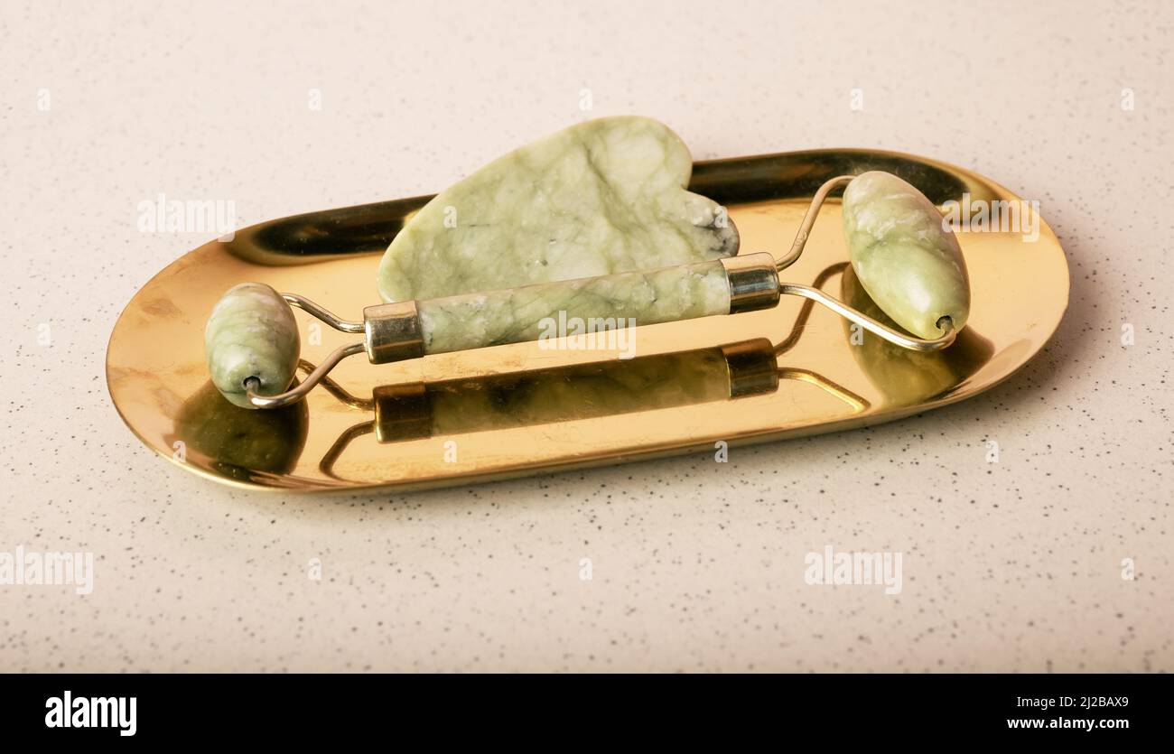 Gua Sha massage stone instruments. Scraper and roller on stand. Face and skin care concept. Lifting and anti-age treatment. Cosmetic natural trend. High quality photo Stock Photo