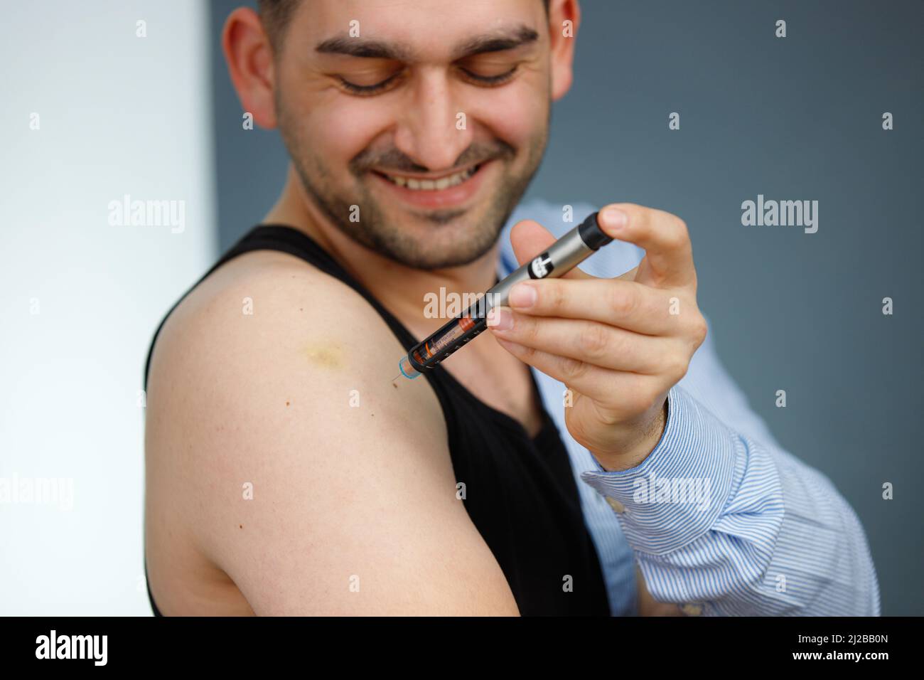 Smiling man making insulin injection to himself at home using syringe