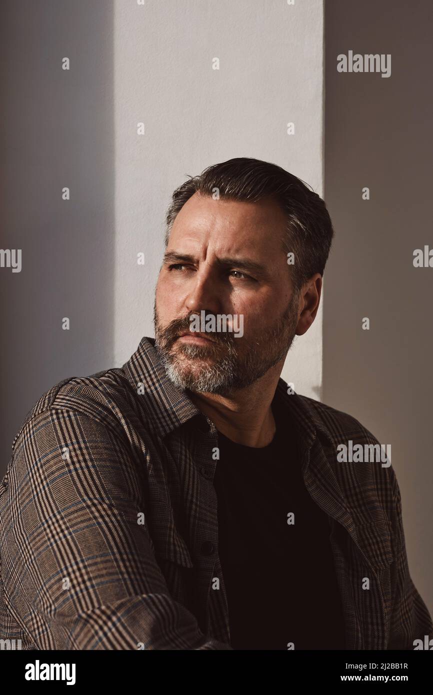 Contemplative mature man against wall Stock Photo